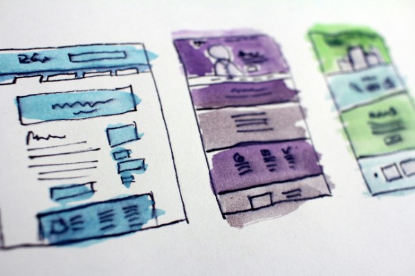 A designer sketching out a website wireframe on paper
